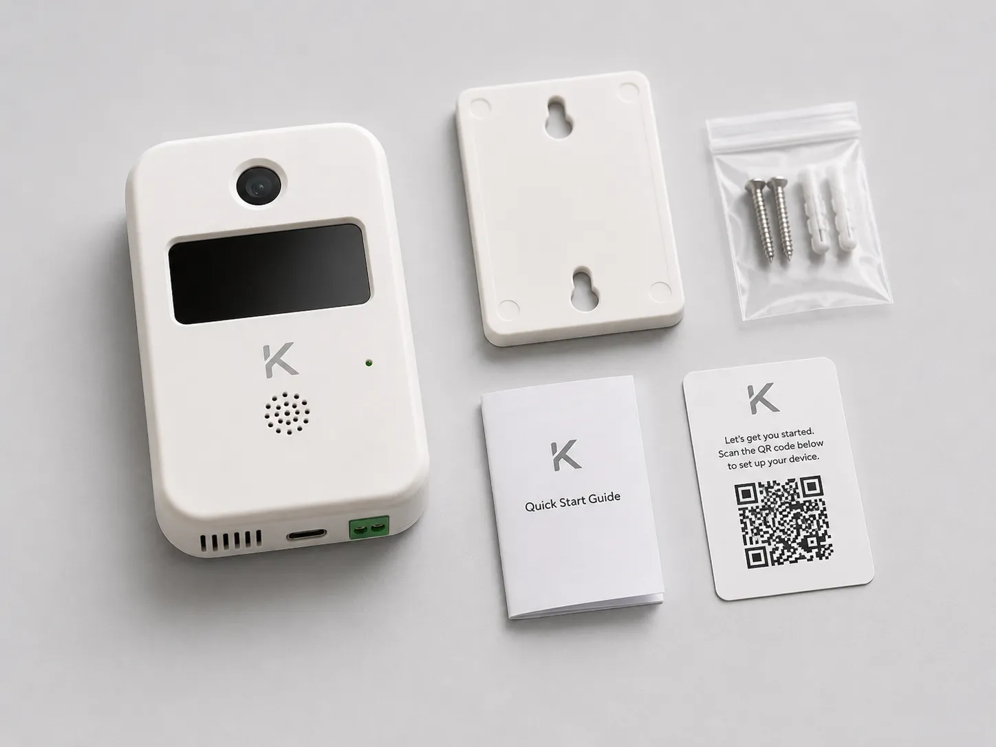 The Kamenet kit laid out on a bench: the wall sensor, a mounting bracket, four screws, a quick-start guide, and the inspector QR card.